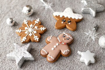 Fototapeta na wymiar Flat lay set of ginger and cinnamon cookies: gingerbread man, snowflakes, stars decorated with icing on grey background with xmas toys. Sweet present for Christmas day.