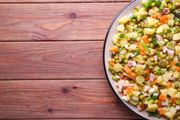 Traditional Russian salad Olivier for Christmas and New Year on a wooden background with place for text
