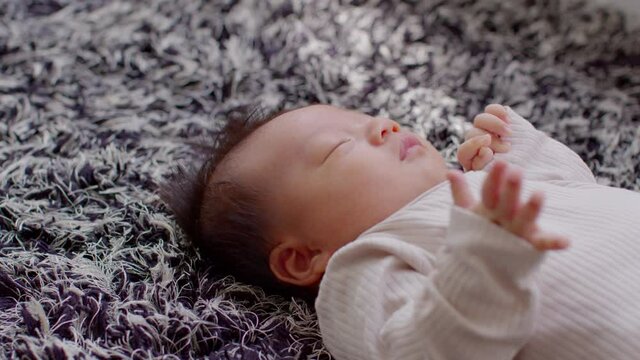 Side view happy newborn baby lying on a carpet looking at camera and smile comfortable and safety.Happiness Cute Asian newborn sleeping and napping on carpet.Newborn Baby photography concept