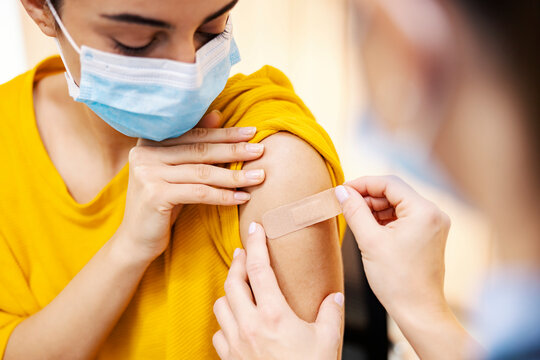 Global immunization and health care. The close-up of the nurse putting adhesive bandage plaster on the girl's arm after injection covid 19 vaccine.