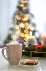 A Cup of Hot drink and in the background blurred candles and a christmas tree