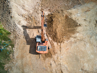 orange excavator at construction site - top view