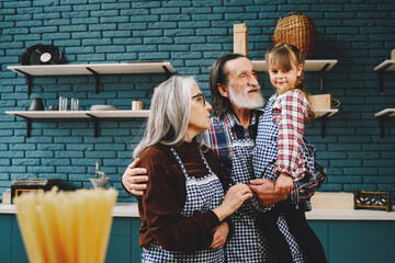 Senior grandparents couple with dgranddaughter cooking in kitchen
