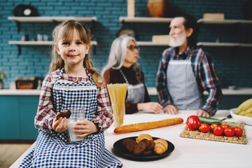 Little girl eating in the kitchen with granparents