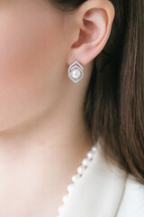 Trendy silver earrings  on a beautiful young girl with long dark hair. Beauty and fashion 