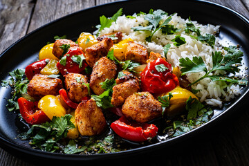 Fried chicken nuggets with white rice, bell peppers and parsley on wooden table