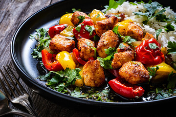 Fried chicken nuggets with white rice, bell peppers and parsley on wooden table