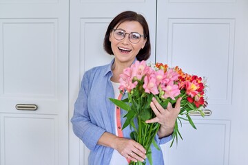 Portrait of a middle aged smiling woman with a bouquet of flowers