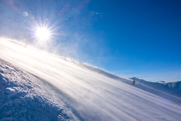 Lone Skier on a Sunny Slope and Blizzard