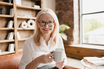 Caucasian middle-aged mature psychologist listening to clients patients while drinking coffee in...