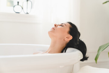 Rejuvenation in spa after work. Serene caucasian mature middle-aged woman relaxing resting in bath warm water at home