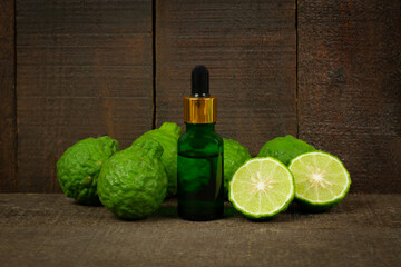 Bergamot oil in green bottle and fresh bergamot fruit on rustic wooden background.