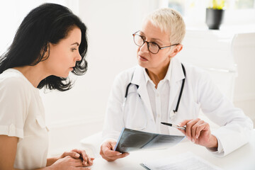 Bad news, negative test results for female mature patient talking with senior doctor general...