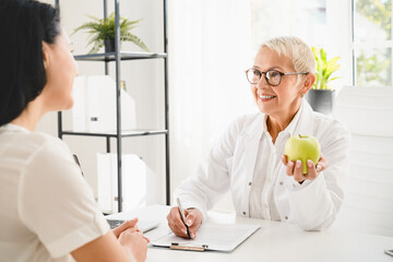 Healthy balanced diet eating concept. Caucasian elderly senior female doctor dietitian nutritionist...