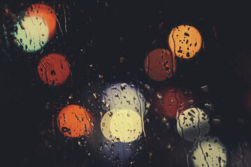 City view through a window on a rainy night,Rain drops on window with road light bokeh, City life...