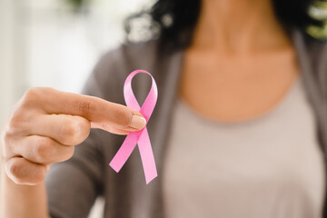 Cropped photo of caucasian woman holding pink ribbon for fighting against breast cancer, supporting...