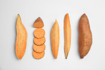 Cut and whole sweet potatoes on white background, top view