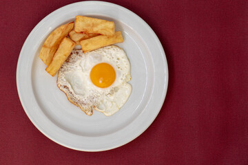 Huevo frito con patatas fritas, sobre plato blanco, visto desde arriba, espacio de copia