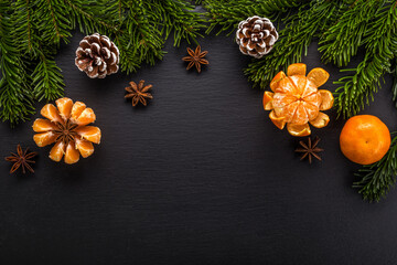 Festive Christmas decoration with fir branches, citrus fruits, star anise at black slate board