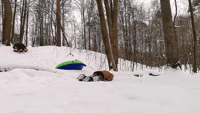 Snow tubing. Tubing in the park in winter. Trick - dad flies over his lying son, and one tube flies into the camera.