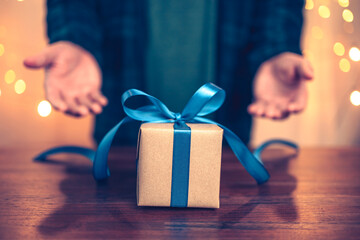 Hands holding gift box, present on the table and light of bokeh background. Valentine's Day,...