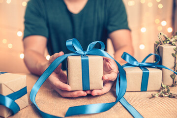 Hands holding gift box, present on the table and light of bokeh background. Valentine's Day,...