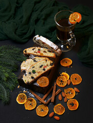 Traditional Christmas cake decorated with frosting, candied fruits, tangerines and cinnamon, place for text. Banner design. selective focus, photography in low key. aromas of the new year.
