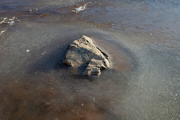 Rock and frozen creek in middle of water. winter landscape. cold weather.