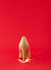 Creative idea made of high heel shoe and cigarette with sprklers against red background. Minimal celebration New Year or Chriistmas party concept. Copy space.