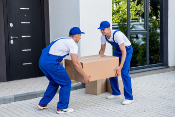 Two removal company workers are loading boxes into a minibus.