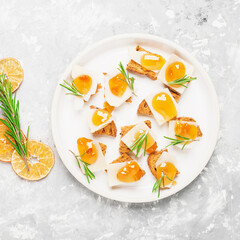 Delicious appetizer, tapas. Parmesan cheese slices on crispy toast with tangerine orange jam and rosemary.