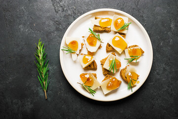 Delicious appetizer, tapas. Parmesan cheese slices on crispy toast with tangerine orange jam and rosemary.