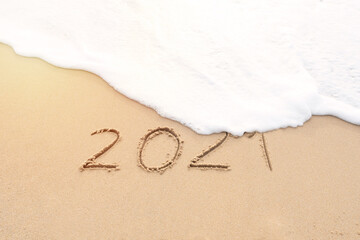 Handwritten 2021 on beautiful sand beach. Goodbye 2021 concept