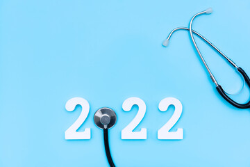 Flat lay of happy new year 2022. Number 2022 with stethoscope on blue background. health medical and new normal lifestyle concept. Copy space, top view