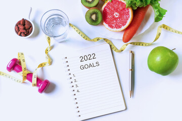 Flat lay of fruits, vegetables, dumbbell ,tape measure and a glass of water on white table...