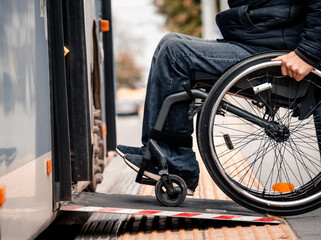Person with a physical disability enters public transport with an accessible ramp. - obrazy, fototapety, plakaty