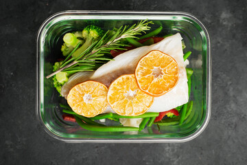White cod fish fillet box. Fresh vegetables with a slice of cod in a glass container. Top view.