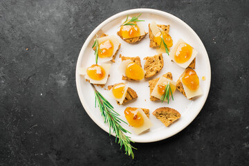 Delicious appetizer, tapas. Parmesan cheese slices on crispy toast with tangerine orange jam and rosemary.