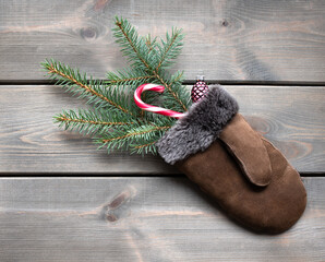 Fototapeta na wymiar glove with fir branch and candy cane on wooden background