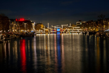 Amsterdam by night with the illuminated Tiny Bridge at the Amstel in the Netherlands