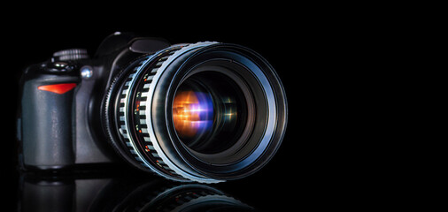 modern DSLR camera and retro telephoto lens close up on black background with reflection