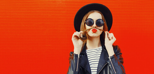 Portrait of funny young woman showing mustache her hair blowing lips with red lipstick having fun...