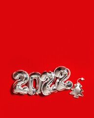 New Year 2022 silver balloons number and soft toys shape as Christmas tree and bright star on red...
