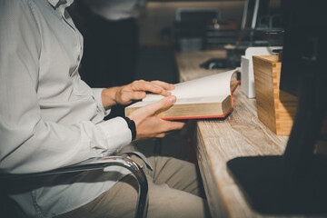 Fototapeta premium Close up, Africa american businessman or student looking at laptop holding book learning, serious black woman working or studying with computer. Learning investment business concept