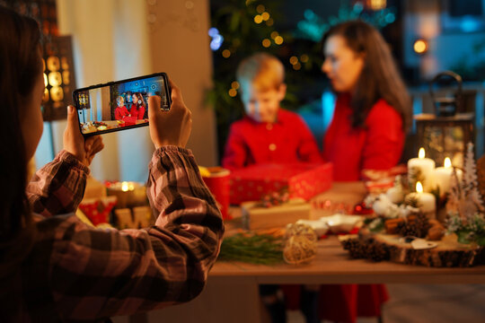 Cheerful daughter taking a picture of her mother and brother - Christmas concept