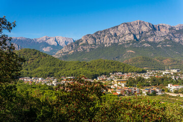 Fototapeta na wymiar view and of the town in a mountain valley (Kemer, Turkey) with Mount Tahtali (Lycian Olympus) in the distance