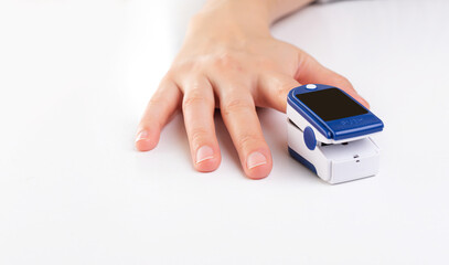 Pulse oximeter on a finger on a white background.