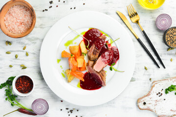 Baked duck breast with celery root and vegetables on a white plate. Top view. Rustic style.