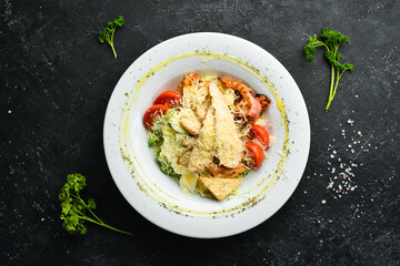 Caesar salad with chicken and bacon. Top view. On a dark background.