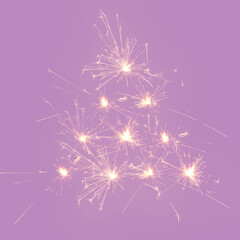 Creative Christmas tree shaped from sprinklers sparks on a dim purple backgrund. Minimal New Year concept.